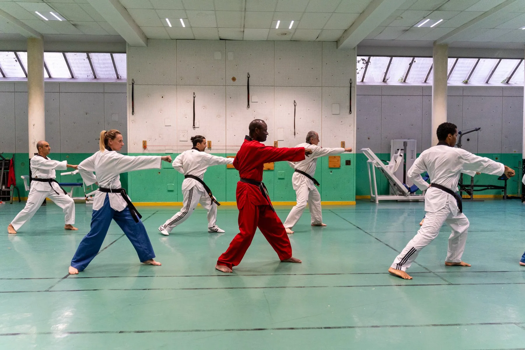 Cours adultes – poomsae en ligne, coup de poing tendu, l'instructeur en dobok rouge au centre