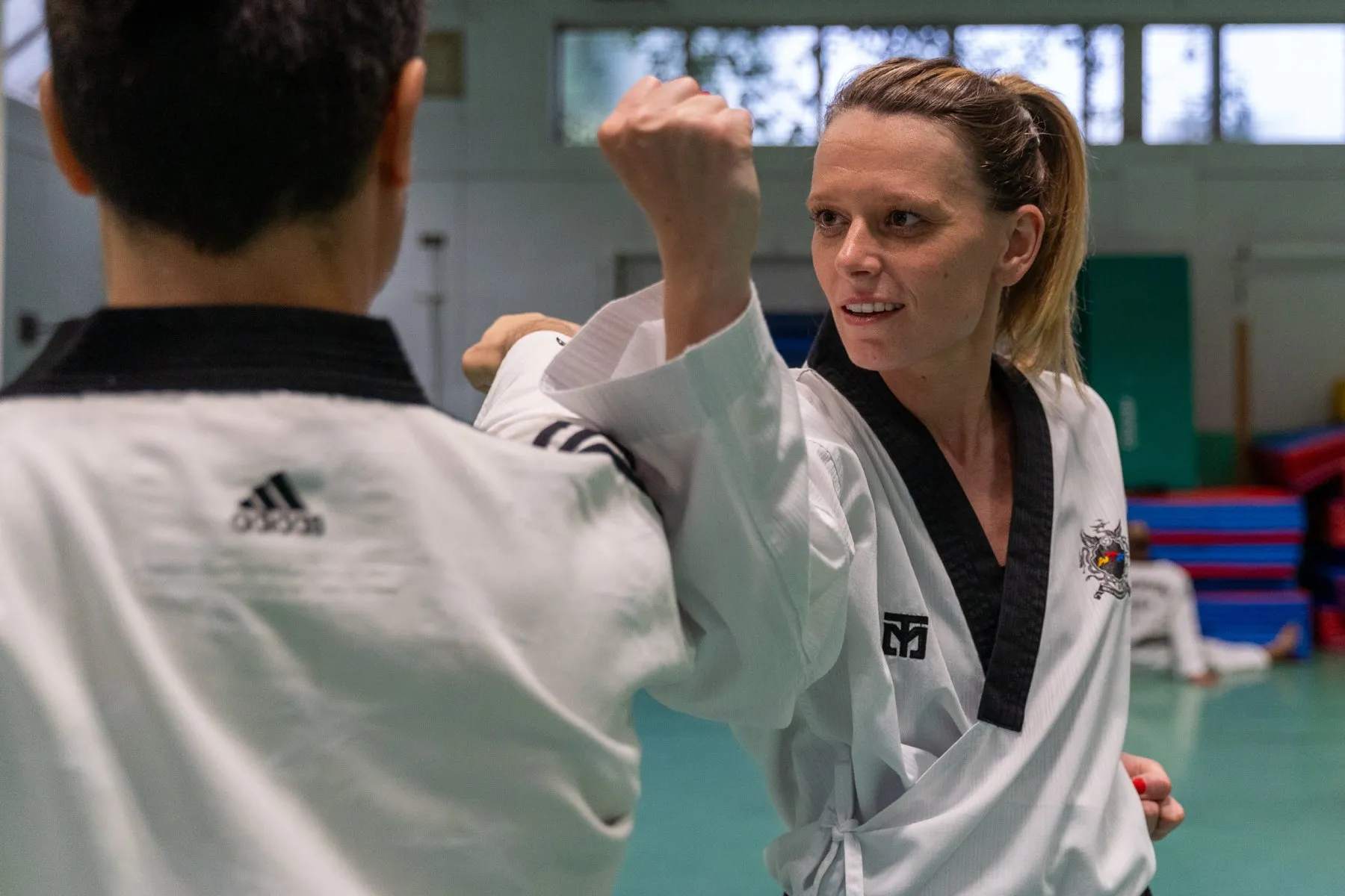 Une pratiquante en dobok, poing levé en garde, face à son partenaire